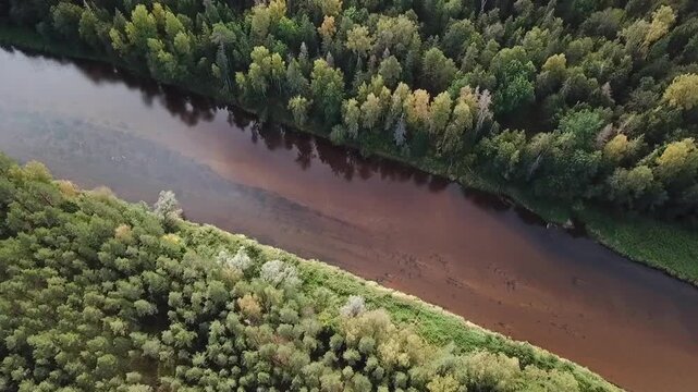 River Gauja running diagonally from upper left to lower right, top-down drone clip, Latvia
