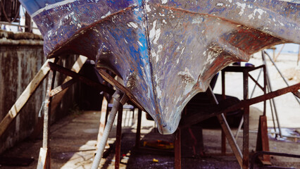 The blue hull of a motorboat propped up on metal stands for maintenance © Наталья Добровольска