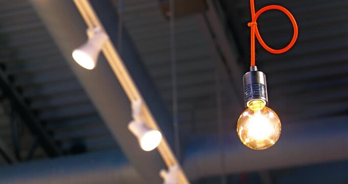 Glowing Edison bulb on orange cord with industrial track lighting