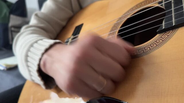 Person hitting acoustic guitar body with palm close up at home, producing strong rhythmic percussion sound, improvised music activity, creative hobby concept