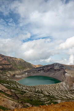 Dramatic Vertical View of Emerald Green Crater Lake Under a Dynamic Cloudy Sky