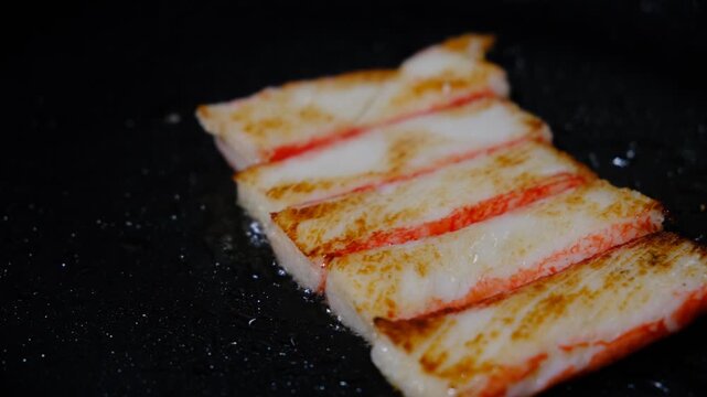 Kanikama. Snow crab immitation, surimi sticks frying. Iron cast pan. Seafood
