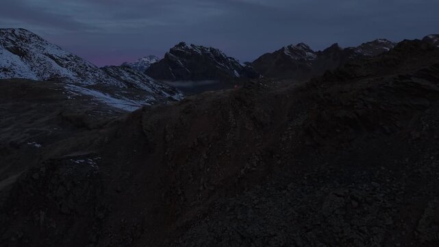 Aerial flyover over a remote alpine hut at dawn in the Swiss Alps with a panoramic view of the mountains and blue sky on an autumn morning