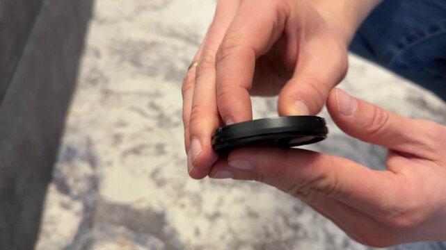 Hands holding camera lens cap close up, photography accessory for lens protection and equipment storage concept