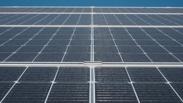 Rows of high efficiency bifacial solar panels at industrial power farm station. Photovoltaic modules generate clean renewable energy for grid supply system under bright sun daylight.