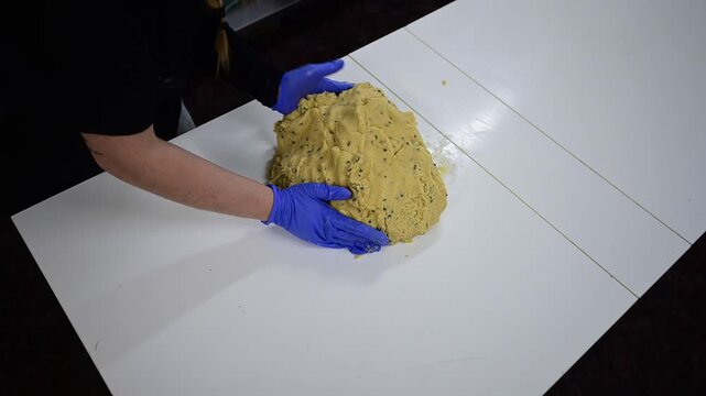 Professional baker kneading a large cookie dough batch