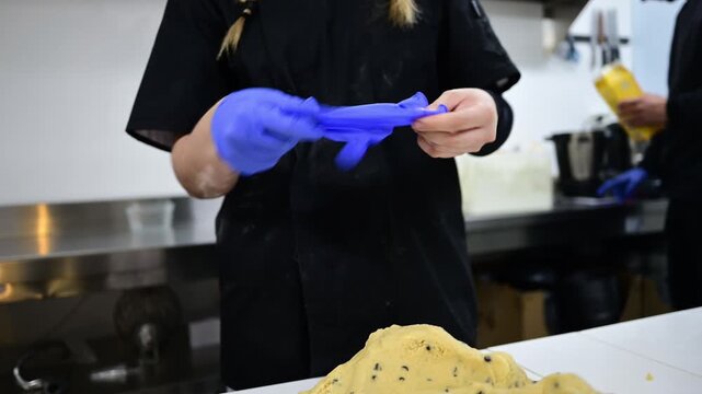 Female pastry chef putting on protective gloves for baking
