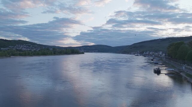 Cinematic drone flight over Rhine River with bird crossing at sunset in Rudesheim
