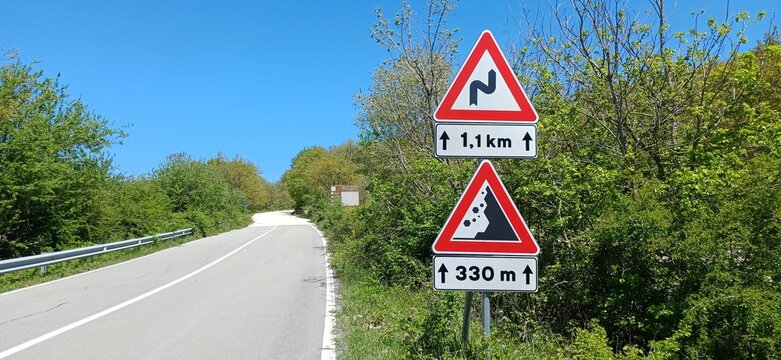 Europ&auml;ische Warnschilder vor gef&auml;hrlichen Kurven und Steinschlag an einer kurvenreichen italienischen Bergstra&szlig;e