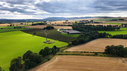 Aerial View of Scottish Farmland with Wind Turbine and Farm Buildings © blueringmedia