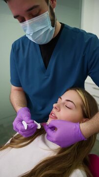 Aesthetic doctor injecting hyaluronic acid filler in woman's lips