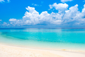 Beautiful turquoise sea with clean white beach sand and water reflecting sky clouds © didecs