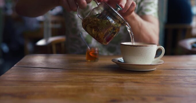 Relaxing morning scene with unrecognizable man drinking herbal tea in a cozy cafe