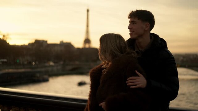 A romantic couple embraces on a bridge in Paris France with the Eiffel Tower visible in the background at sunset The shot pans across the scene showcasing the lovers enjoying their time together on th