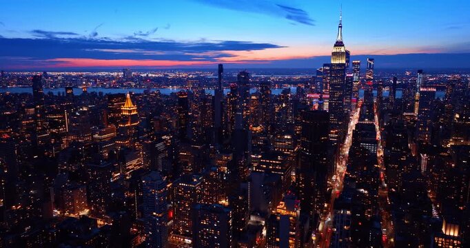 Flying over the gorgeous cityscape of New York City at night. Approaching the Empire State Building with neon illumination.