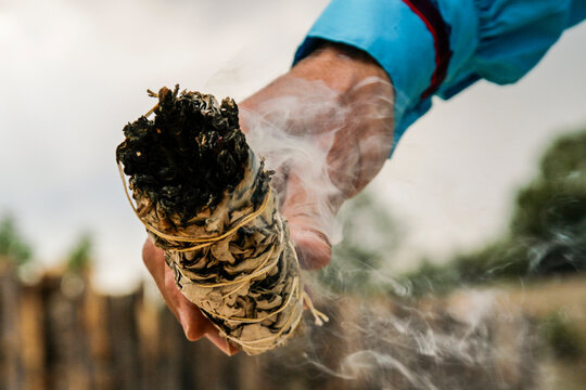 Smoking sage bundle held during traditional cleansing ritual