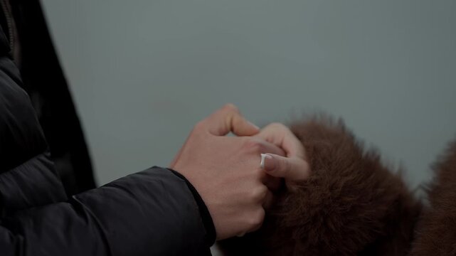 Close-up shot of a couple holding hands in Paris France The woman has a white manicure and is wearing a brown fur coat The scene captures a romantic moment filled with love and affection.