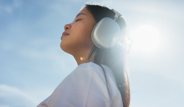 Young woman with headphones enjoying quiet relaxation in sunlight