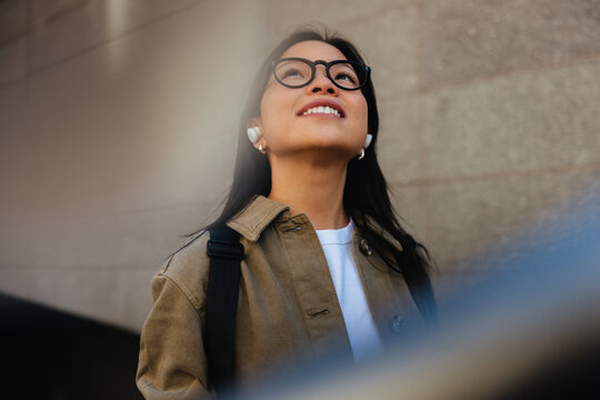 Young woman smiling while listening with wireless earbuds