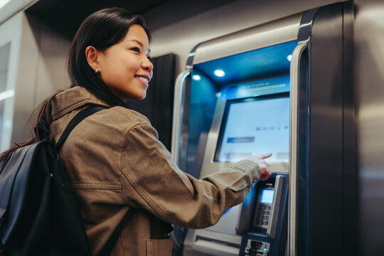 Young woman using transit ticket machine at station