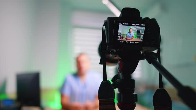 Professional camera on tripod with a man on the display. Medic creates video for his blog. Blurred backdrop.