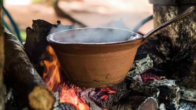 Cooking in traditional clay pot over open fire, primitive cooking method in rural area