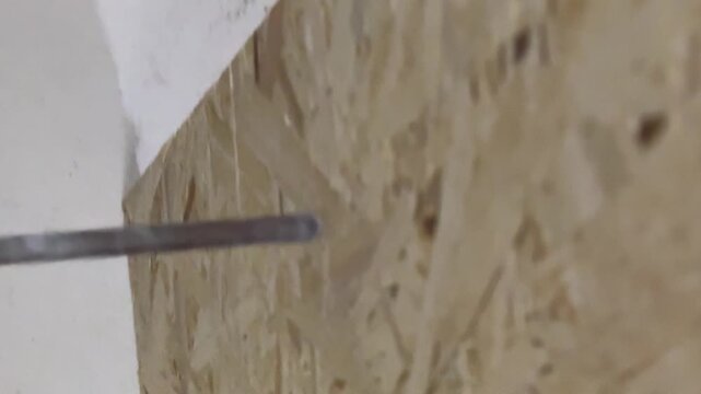 electric drill drilling into chipboard panel in close up, woodworking and furniture assembly process, DIY construction concept