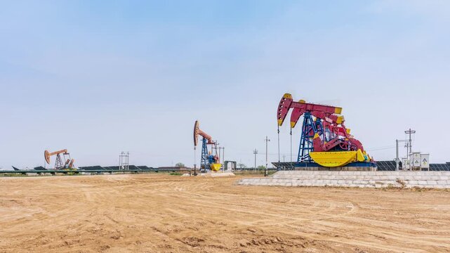 Time-lapse of colorful beam pumping units operating in beach oil field under clear sky  