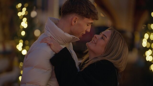 A romantic young couple embraces in Paris France at night with bokeh lights showing love and affection. This image is perfect for Valentine's Day winter holidays and romance concepts.