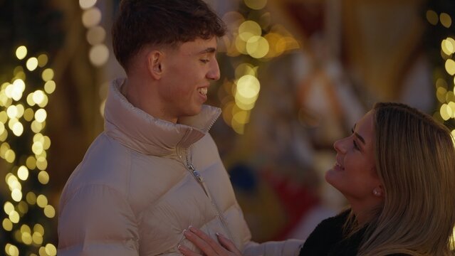 A romantic young couple in Paris France enjoys the Christmas market lights and festive atmosphere sharing a moment of love and happiness together. This image is perfect for illustrating travel romance