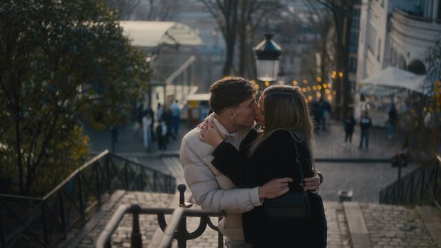 A romantic couple kisses on the steps of Montmartre in Paris France during the autumn season. This image is perfect for travel and tourism stock photography and creative content.