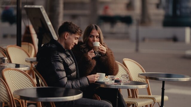 A romantic couple enjoys coffee at an outdoor in Paris France The woman is drinking a latte while the man holds a cup of coffee showcasing love and connection in an urban setting.