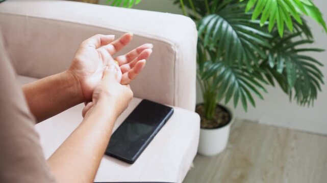 Female hand massaging painful palm and wrist after texting on a smartphone. Concept of muscle strain, numbness, carpal tunnel syndrome, and trigger finger symptoms caused by improper ergonomics 