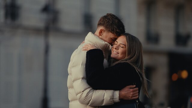 A young couple embraces affectionately in Paris France showcasing love and connection in an urban setting. This image is suitable for travel lifestyle and relationship contentment.