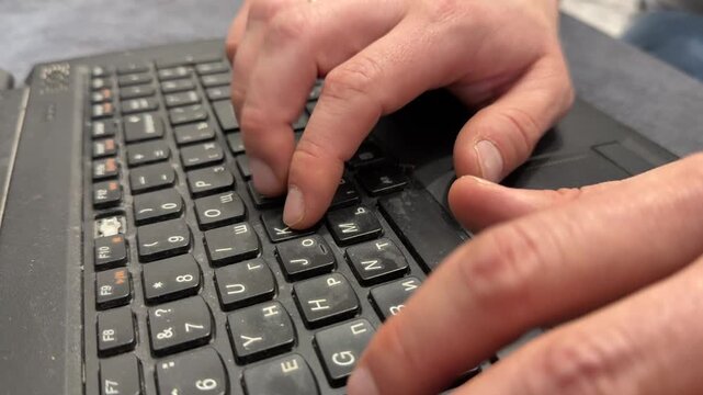 Hands typing on old laptop keyboard close up, outdated computer use for remote work and productivity concept