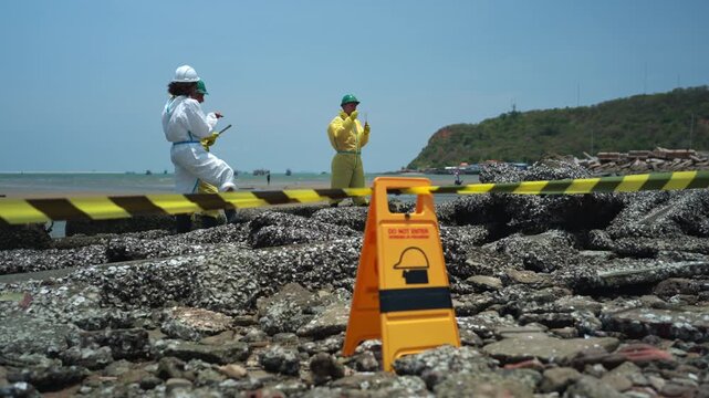 Environmental response team in hazmat suits analyzing coastal water samples and monitoring marine pollution near industrial shoreline