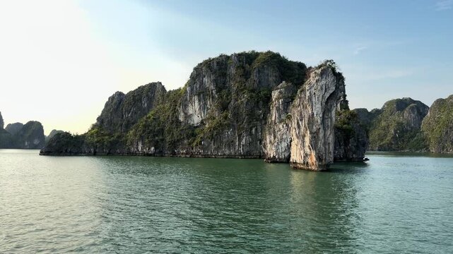Limestone karst islands rising from calm turquoise waters of Halong Bay Vietnam, peaceful seascape, natural scenery, travel destination, heritage site