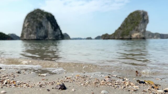 Seaside view with seashells on sandy shore and karst limestone islands in the background, tropical ocean landscape, coastal scenery in Vietnam