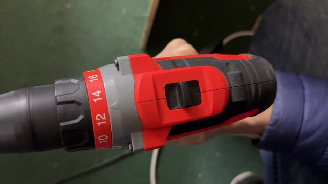 Close up of woman hand using electric screwdriver, pressing trigger and rotating tool, fastening process and power tool usage concept