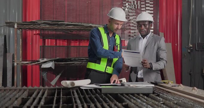 Sales engineer meets a client in an industrial workshop, reviewing quotation details, discussing costs and capabilities, and negotiating terms for a custom production project.
