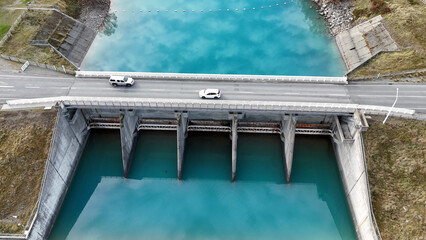 Fototapeta premium Aerial View of Cars Crossing Lake Tekapo Dam Bridge in New Zealand