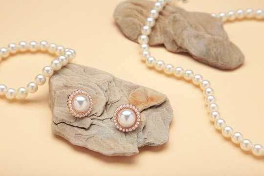 Beautiful pearl earring and necklace on stone on beige background