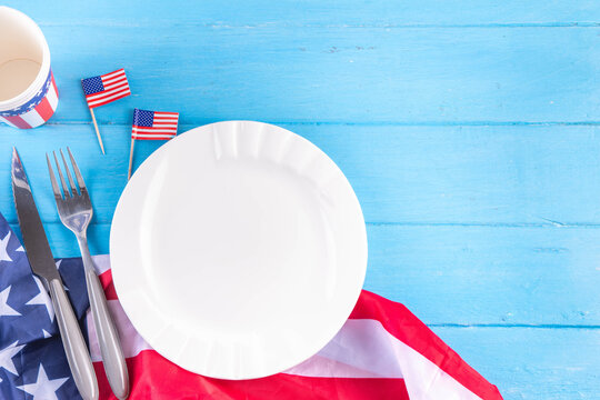USA patriotic table setting with american flag, plate and decoration in national flag colors on white background. Independence Day. Happy Memorial Day dinner menu background top view copy space