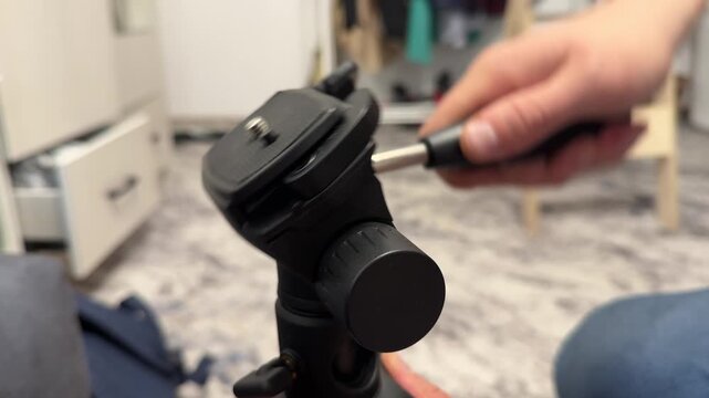 Hand attaching quick release plate to tripod head, camera support setup and photography equipment concept