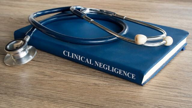 Clinical Negligence concept featuring a medical law textbook with a professional stethoscope on a rustic wooden office desk.