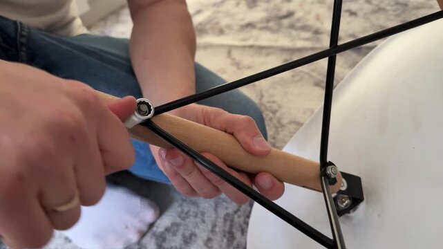 Person repairing chair using wrench, tightening fasteners and fixing furniture structure, home maintenance and manual work concept indoors