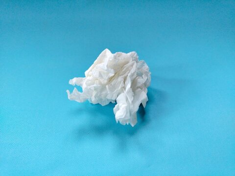 crumpled used paper tissue on blue