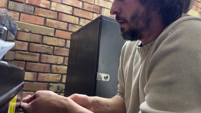 Man using screwdriver on equipment near wall, repair and maintenance concept, working with tool and device indoors, close up technical activity