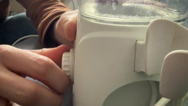 Hand adjusting water flosser mode selector, setting oral irrigator pressure on dental hygiene device concept