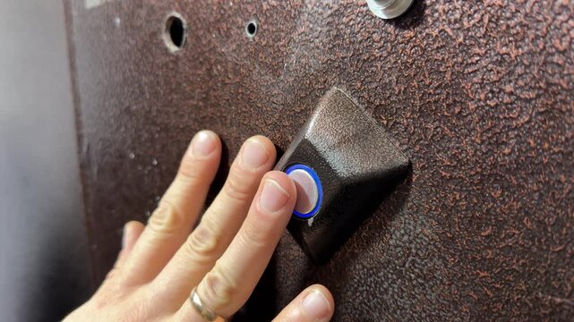 Person pressing door opening button on intercom panel close up outdoors, unlocking entrance door, access control action, security technology use